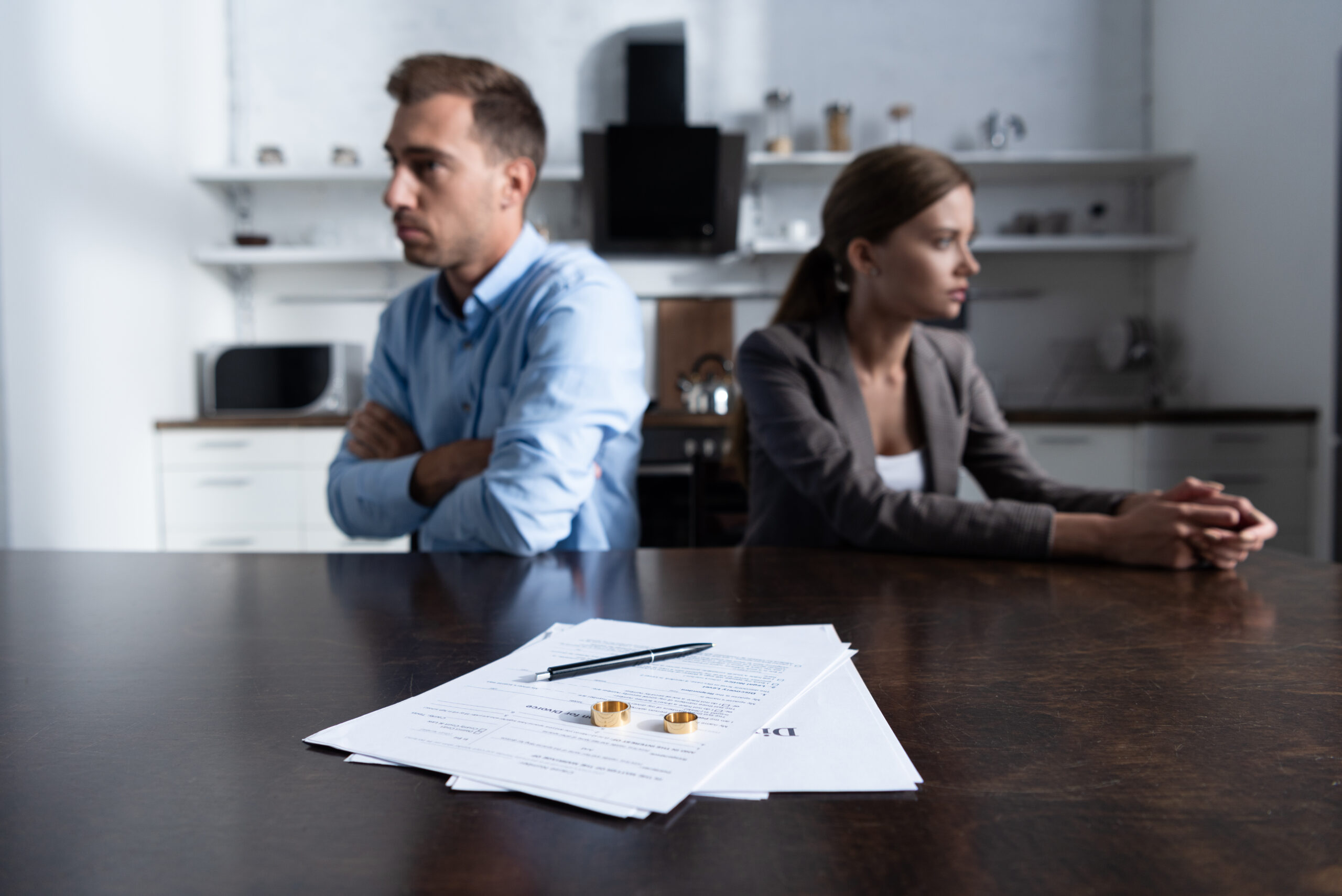 selective focus of couple sitting at table with divorce documents